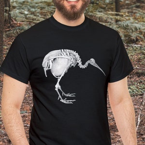 May include: A black t-shirt with a white graphic of a kiwi bird skeleton. The bird is walking with its head turned to the side.