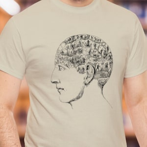 May include: A beige t-shirt featuring a black and white illustration of a human head with a detailed anatomical drawing of the brain.