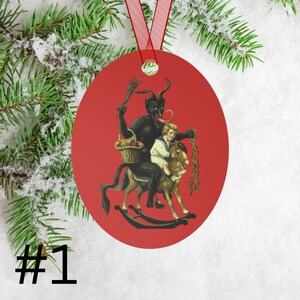 May include: Red round Christmas ornament featuring a black devil figure riding a rocking horse with a child on its back. The devil has a long red tongue and is holding a basket of fruit. The child is wearing a white sailor shirt and is holding the reins of the horse.