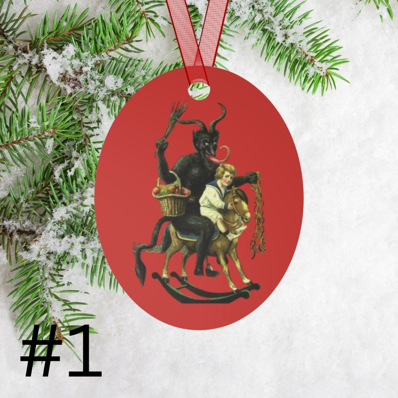May include: Red round Christmas ornament featuring a black devil figure riding a rocking horse with a child on its back. The devil has a long red tongue and is holding a basket of fruit. The child is wearing a white sailor shirt and is holding the reins of the horse.