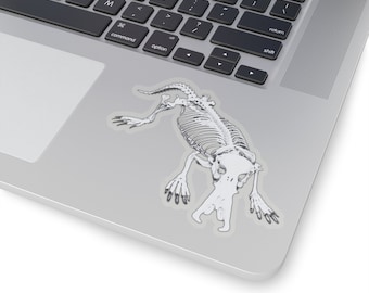 Pode incluir: Uma ilustração em preto e branco de um esqueleto de ornitorrinco em um laptop prateado.