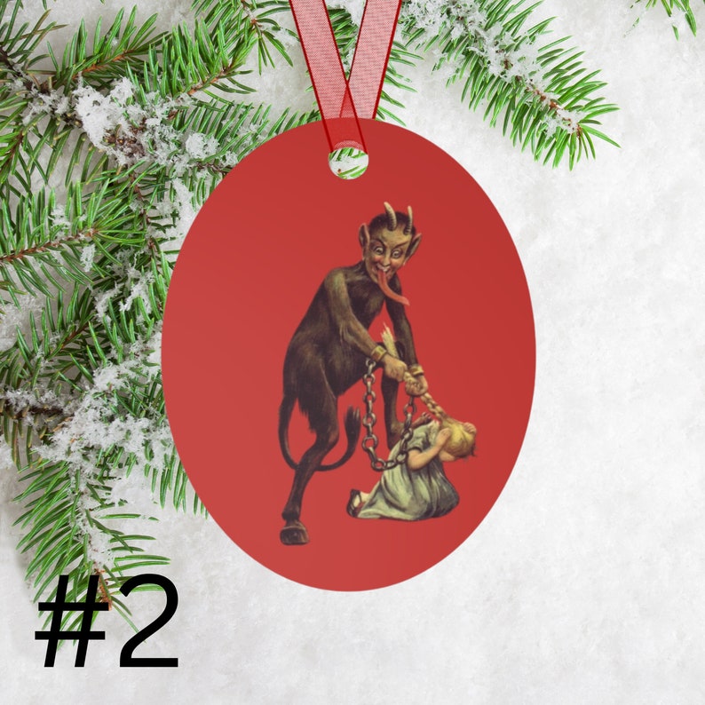 May include: Red round Christmas ornament with a vintage illustration of a devil pulling a young girl by her hair with a chain.