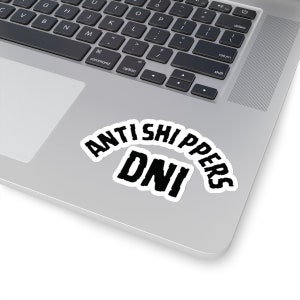 May include: A white laptop with a black sticker that says "ANTI SHIPPERS DNI" in a bold, black font.