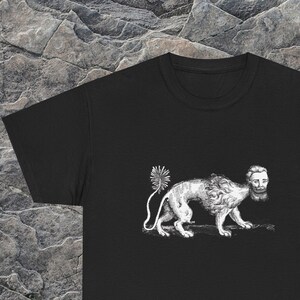 May include: Black t-shirt featuring a detailed white illustration of a lion with a human head and a burst-like tail. The design is a unique, artistic graphic.