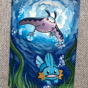 May include: A hand-painted illustration of two Pokemon, a blue and orange Mantine and a blue and orange  Mudkip, swimming in a blue and green ocean with white bubbles.