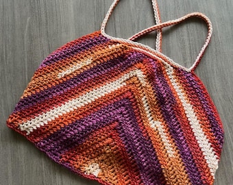 May include: A crocheted halter top with a geometric pattern in shades of orange, purple, and white.