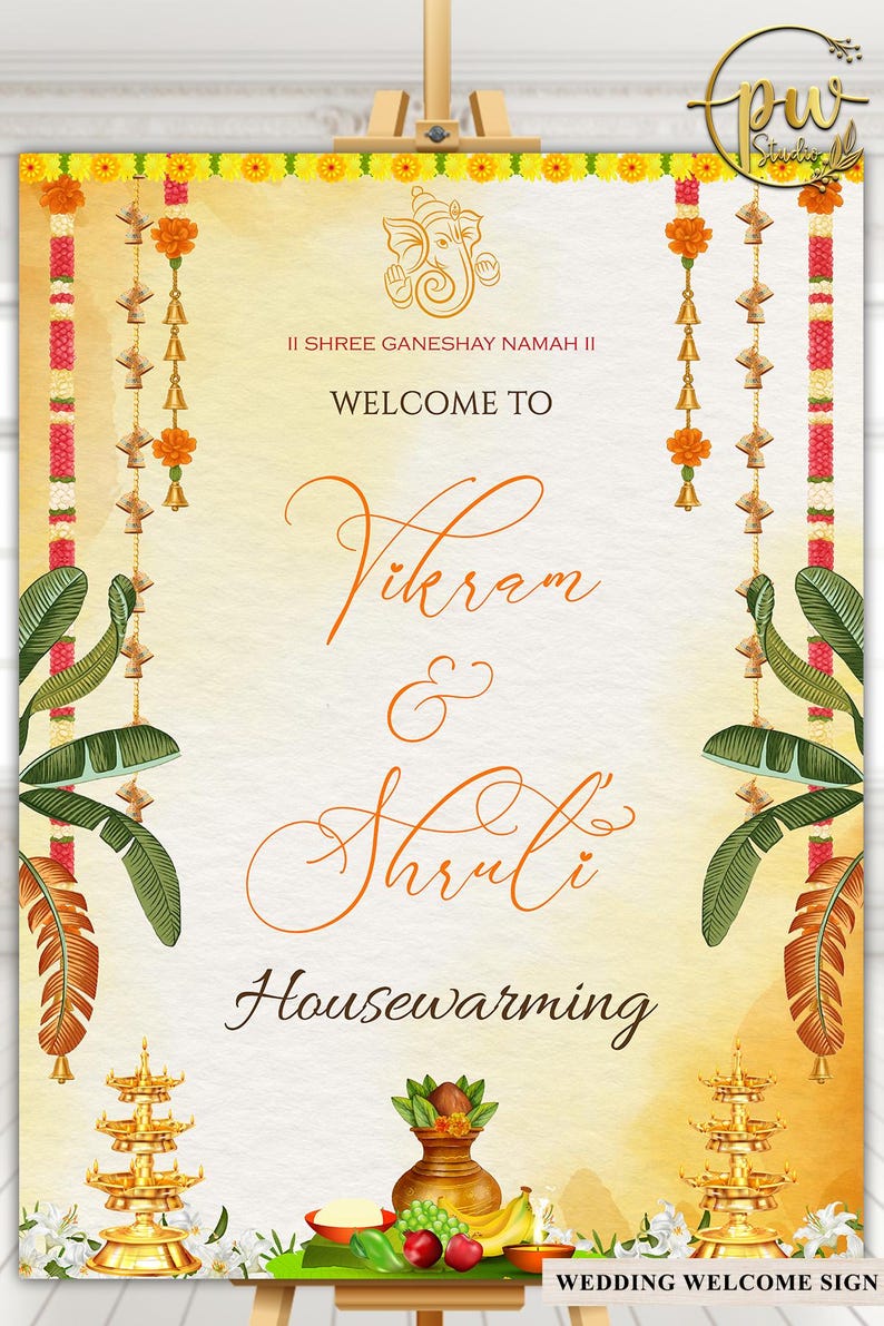 May include: A wedding welcome sign with a warm, yellow and orange gradient background. The sign features the names "Vikram & Shruti" in elegant script, with floral and decorative elements. The text "Welcome To" and "Housewarming" are also visible.
