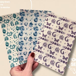 May include: Three patterned fabric sheets with celestial and botanical designs. One sheet features teal mushrooms, moons, and stars. Another has blue moons, stars, and mushrooms. The third has purple butterflies, moons, and snakes.