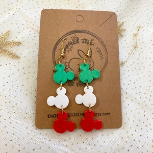 May include: Green, white and red Mickey Mouse-shaped dangle earrings. The earrings are made of polymer clay and have gold hooks.
