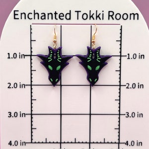 May include: A pair of black and green dragon earrings with gold hooks. The earrings are approximately 1 inch in length.