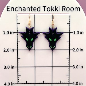 May include: A pair of black and purple dragon earrings with green eyes. The earrings are approximately 1.5 inches long and are hanging from gold hooks.