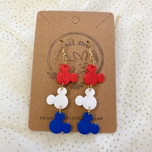 May include: Red, white and blue Mickey Mouse-shaped earrings. The earrings are made of polymer clay and have gold hooks.