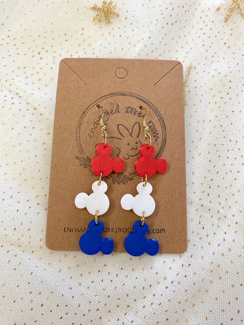 May include: Red, white and blue Mickey Mouse-shaped earrings. The earrings are made of polymer clay and have gold hooks.