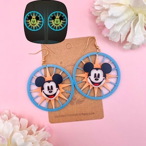 May include: A pair of blue and orange Mickey Mouse earrings with a sunburst design. The earrings are on a brown card with the text "EnchantedDickiRoo.etsy.com".