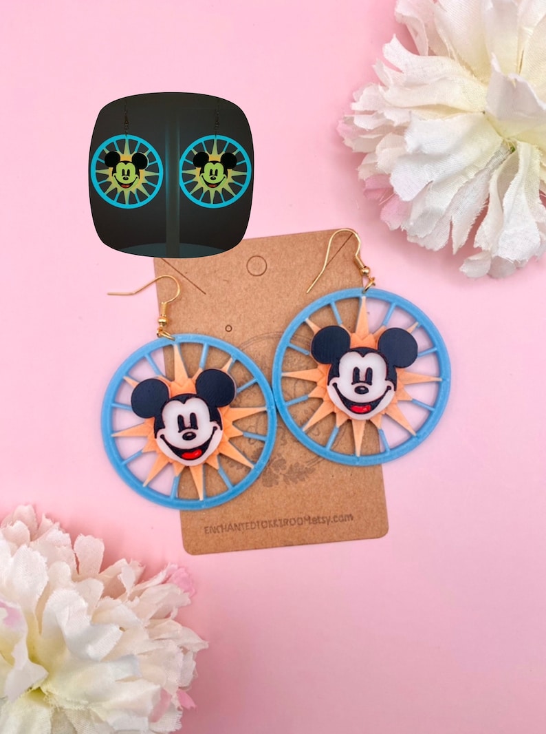 May include: A pair of blue and orange Mickey Mouse earrings with a sunburst design. The earrings are on a brown card with the text "EnchantedDickiRoo.etsy.com".