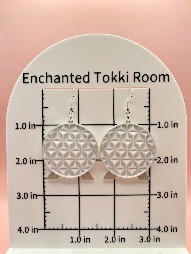 K&ouml;nnte beinhalten: Ein Paar silberfarbene H&auml;ngeohrringe. Jeder Ohrring ist ein Kreis mit einem geometrischen Muster. Die Ohrringe haben einen Durchmesser von etwa 5 cm und h&auml;ngen an silbernen Haken. Der Text "Enchanted Tokki Room" ist im Hintergrund sichtbar.