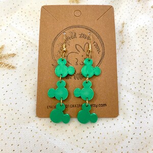 May include: Green dangle earrings with three Mickey Mouse head shapes on each earring. The earrings are made of polymer clay and have gold hooks.