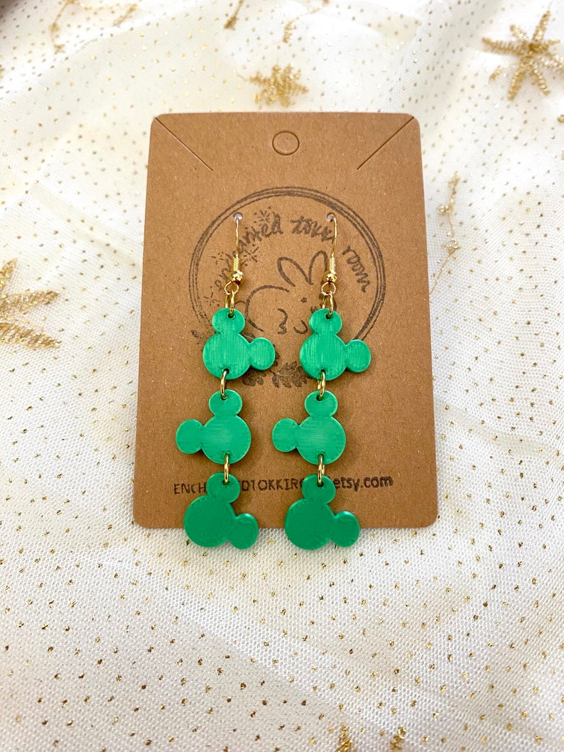 May include: Green dangle earrings with three Mickey Mouse head shapes on each earring. The earrings are made of polymer clay and have gold hooks.
