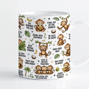 Pode incluir: Uma caneca de cerâmica branca com um padrão repetitivo de macacos castanhos, folhas tropicais verdes, bananas amarelas e cocos. O design inclui frases inspiradoras como Go Bananas For Life, Swing Into Happiness e Life Is Better Together.