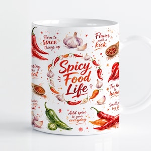 Puede incluir: Una taza de cerámica blanca con una colorida ilustración en acuarela de varios chiles y dientes de ajo. El texto "Spicy Food Life" está centrado, rodeado de frases como "Born to spice things up" y "Flavor with a kick" en color rojo.