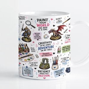 Puede incluir: Una taza de cerámica blanca con un patrón colorido de suministros para pintar miniaturas, que incluye una figura de dragón, un caballero, pinceles, paletas y textos inspiradores como Paint Your World One Mini At A Time.