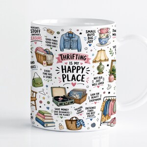 May include: A white ceramic mug featuring a colorful, detailed illustration of thrift store items including a denim jacket, record player, books, and baskets. The text reads, "THRIFTING IS MY HAPPY PLACE," surrounded by small icons and phrases.