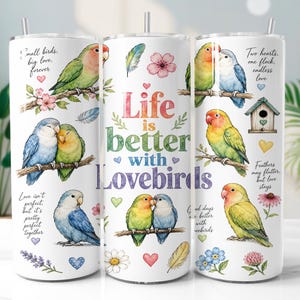 Può includere: Un bicchiere cilindrico bianco con illustrazioni ad acquerello di inseparabili appollaiati su rami, motivi floreali e cuori. Il testo recita: Life is better with Lovebirds, Small birds, big love, forever, Two hearts, one flock, endless love.
