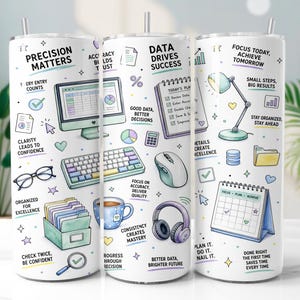 May include: A white cylindrical tumbler with a straw featuring colorful illustrations of office supplies including a computer, keyboard, mouse, headphones, desk lamp, calendar, and file folders, along with motivational text like Precision Matters.