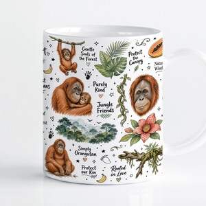 Può includere: Una tazza in ceramica bianca con una colorata illustrazione di oranghi, fogliame tropicale e frutta. Il testo include frasi come Gentle Souls of the Forest, Protect the Canopy, Purely Kind, Jungle Friends, Simply Orangutan e Rooted in Love.