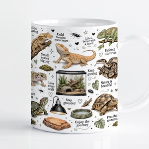 Op de afbeelding: Een witte keramische mok met een kleurrijke illustratie van diverse reptielen, waaronder een baardagame, kameleon, luipaardgekko, schildpad en slang, samen met een terrarium, warmtelamp en teksten zoals "Cold blooded, warm heart."