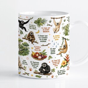 Peut inclure: Un mug en céramique blanche orné d'illustrations colorées de gibbons dans diverses positions, de feuillages tropicaux, de bambous et d'une corbeille de fruits. Le motif inclut des phrases inspirantes numérotées comme Life is better in the trees.
