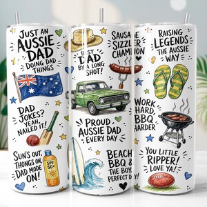 May include: A white cylindrical tumbler featuring a wrap-around design with Australian-themed illustrations including a green pickup truck, a flag, a surfboard, a barbecue grill, flip-flops, a cricket bat, and text such as Just an Aussie Dad.