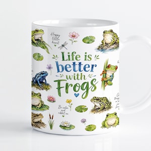 Pode incluir: Uma caneca de cerâmica branca com uma ilustração colorida em aguarela de várias rãs, nenúfares e flores. O texto "Life is better with Frogs" está impresso no centro, acompanhado por frases mais pequenas como "Hoppy little heart" e "Be calm and ribbit on."