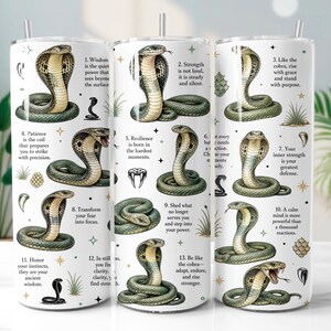 Può includere: Un bicchiere cilindrico bianco con molteplici illustrazioni di cobra verdi e marrone chiaro in varie pose. Il design include tredici citazioni ispiratrici numerate sulla forza e la saggezza, intervallate da piccole icone di stelle e piante.