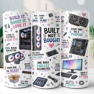 May include: A white cylindrical tumbler featuring a colorful graphic print of computer hardware components, including a PC tower, motherboard, graphics card, and monitor, alongside motivational text like "Built Not Bought" and "Build It. Boost It. Love It."