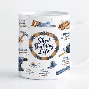 May include: A white ceramic mug featuring a watercolour design of construction tools including a saw, hammer, drill, and tape measure. The text reads Shed Building Life, Crafting sturdy shelters, Measure twice cut once, Built with precision, Strong foundations lasting memories, Every nail counts, and Framing dreams into reality.