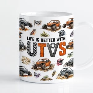 Könnte beinhalten: Ein weißer Keramikbecher mit einem wiederkehrenden Muster aus orangefarbenen und grauen UTVs, Zielflaggen, Helmen und Federbeinen. Der Text "LIFE IS BETTER WITH UTVS" ist mittig aufgedruckt, wobei der Buchstabe U ein Reifenprofil-Muster aufweist.