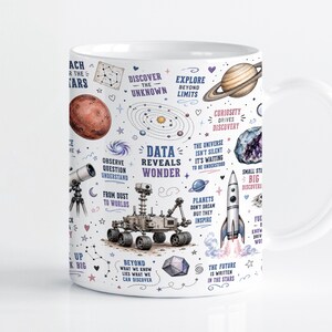Może przedstawiać: Biały ceramiczny kubek z motywem kosmicznym, zawierający ilustracje łazika, rakiety, planet i teleskopu. Na kubku znajdują się napisy takie jak DATA REVEALS WONDER, REACH FOR THE STARS, DISCOVER THE UNKNOWN oraz EXPLORE BEYOND LIMITS.