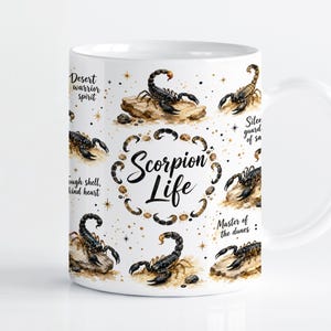 Könnte beinhalten: Ein weißer Keramikbecher mit einem wiederkehrenden Muster aus schwarzen Skorpionen auf sandigen Felsen, goldenen Sternakzenten und dem Text "Scorpion Life" in der Mitte, umgeben von Phrasen wie "Desert warrior spirit" und "Tough shell, kind heart."