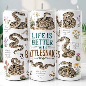 Op de afbeelding: Een witte cilindrische beker met illustraties van bruine ratelslangen, woestijnbloemen en cactussen. De tekst luidt: Life is better with rattlesnakes, Find your wild side, Respect the rattle, Beauty in every scale, Not aggressive, just well prepared.