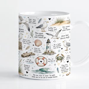 Pode incluir: Uma caneca de cerâmica branca com um padrão de tema costeiro, apresentando ilustrações de gaivotas, um farol, uma boia salva-vidas, um caranguejo, conchas e dunas de areia. O design inclui várias frases inspiradoras em texto preto espalhadas.