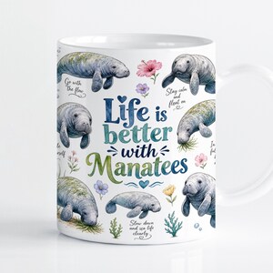 Puede incluir: Una taza de cerámica blanca con ilustraciones en acuarela de manatíes, pequeñas flores coloridas y algas verdes. El texto dice Life is better with Manatees, Go with the flow, Stay calm and float on y Slow down and sea life clearly.