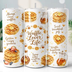 May include: A white cylindrical tumbler featuring watercolour illustrations of waffles, syrup pitchers, and strawberries. Text includes Always crave waffles, Golden crispy goodness, Waffle Lover Life, Syrup makes everything better, Sweet breakfast joy, and Waffle happiness daily.