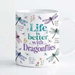 May include: A white ceramic mug featuring colorful illustrations of dragonflies and small wildflowers. The text reads: Life is better with Dragonflies, Find beauty in the little things, Be light, Be free, Be you, Let your dreams take flight, Dare to chase what sets your soul free.