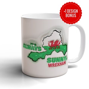 Può includere: Tazza in ceramica bianca con la scritta "It's Always Sunny Wrexham" in verde e rosso. Il design include un contorno della mappa con un drago rosso, simbolo del Galles. Un cerchio rosso con "+1 DESIGN BONUS" è in alto.