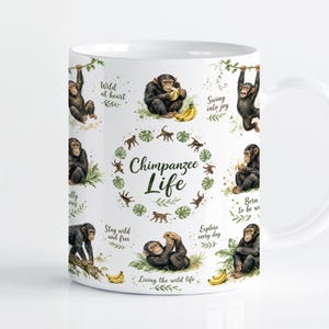 Pode incluir: Uma caneca de cerâmica branca com um padrão repetitivo de chimpanzés em várias poses, bananas amarelas e folhas tropicais verdes. O texto central diz Chimpanzee Life, rodeado por frases que incluem Wild at heart e Swing into joy.