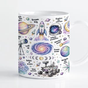 Pode incluir: Uma caneca de cerâmica branca com um padrão espacial colorido, apresentando ilustrações de planetas, um foguete, um capacete de astronauta, um telescópio, uma galáxia e um rover. O design inclui frases como Dream big, Explore the unknown e Look up.