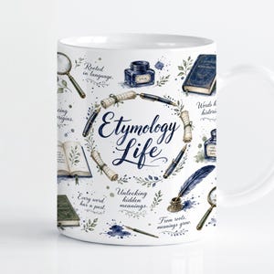 Op de afbeelding: Een witte keramische mok met een blauw en zwart aquarelontwerp met de tekst Etymology Life. De illustratie bevat inktpotten, ganzenveren, vergrootglazen, rollen en boeken met zinnen zoals Rooted in language.