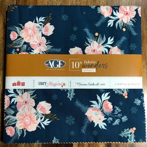 May include: A stack of fabric squares with a dark blue background and a floral pattern in pink and white. The fabric is labeled "10" fabric wonders" with 42 pieces. The text "COZY Magical" is also visible.