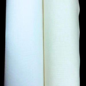 May include: Two rolls of fabric, one a pale blue and the other a creamy off-white, are displayed against a black background. The fabric appears to be a tightly woven linen or cotton, with a subtle texture visible in the close-up view.